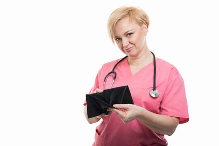 Attractive female doctor wearing pink scrubs holding empty wallet looking happy isolated on white background with copyspace advertising areaの写真素材