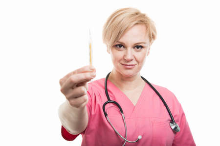 Attractive female nurse wearing pink scrubs showing thermometer isolated on white background with copyspace advertising areaの写真素材