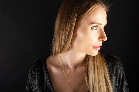 Portrait of beautiful female model posing looking sexy on black background with copypsace...