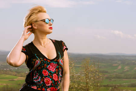 Portrait of cool fashionable woman posing in the wind on countryside background in sunlight with copyspace advertising areaの写真素材