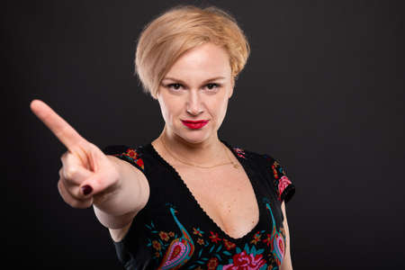 Portrait of cool fashionable woman showing denial gesture with index finger on black background with copypsace advertising areaの写真素材