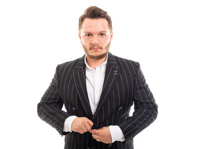 Portrait of young business man buttoning up jacket isolated on white background with copyspace advertising areaの写真素材