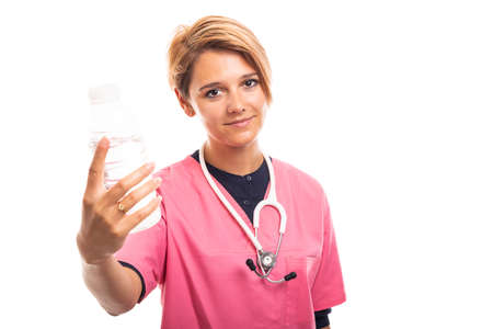 Portrait of female vet wearing pink scrub showing a bottle of water isolated on white background with copyspace advertising areaの写真素材
