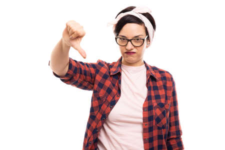 Portrait of young pretty pin-up girl wearing glasses showing thumb down gesture isolated on white...