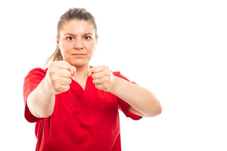 Portrait of young medical nurse wearing red scrub showing both fists gesture isolated on white...