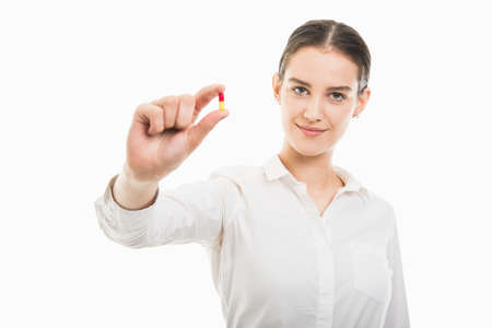 Portrait of young pretty business woman showing a two color pill isolated on white background with copy space advertising areaの写真素材