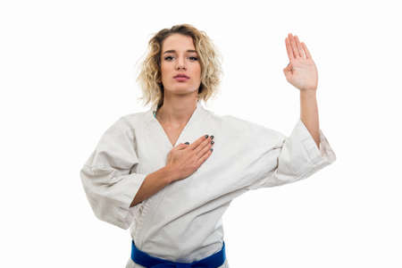 Portrait of female wearing martial arts uniform making oath gesture isolated on white backgroundの写真素材