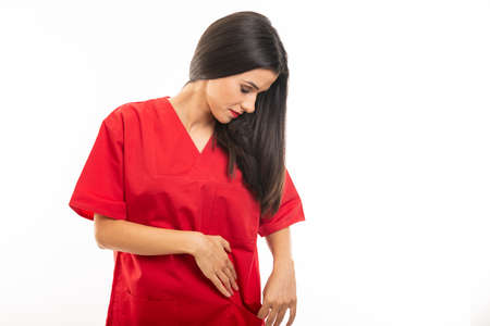 Portrait of beautiful young nurse wearing scrubs looking in pocket isolated on white background with copy space advertising areaの写真素材