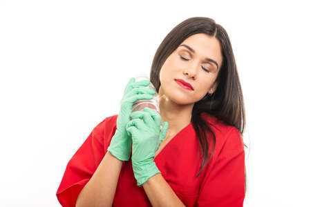 Portrait of beautiful nurse wearing scrubs putting on sterile gloves isolated on white background