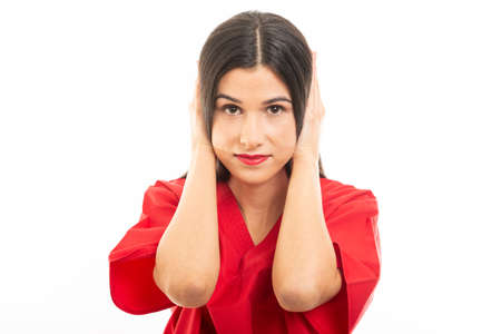 Portrait of nurse wearing scrubs covering ears like deaf concept isolated on white background