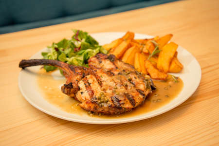 Plate of mutton steak or chops with potato and sauce garnish in bistro or restaurant