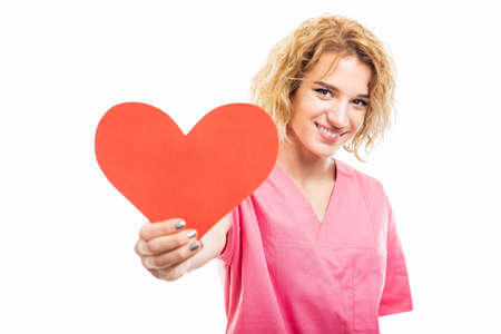 Portrait of nurse wearing pink scrub giving red heart isolated on white background with copy space advertising areaの写真素材