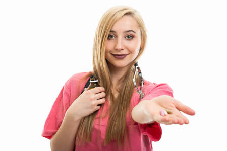 Portrait of female doctor wearing scrubs handing pills isolated on white background with copy space...