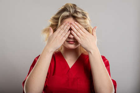 Portrait of nurse wearing red scrub covering eyes like blind concept on studio gray backgroundの写真素材