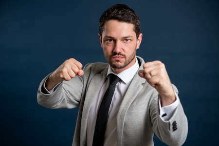Portrait of business young male making fight gesture on blue backgroundの写真素材