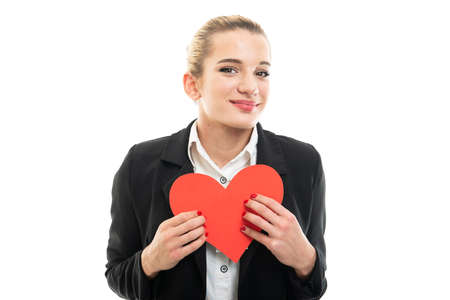 Portrait of beautiful young female assistant manager holding red heart isolated on white background with copy space advertising areaの写真素材