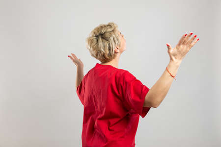 Portrait of young attractive female nurse making winner gesture on grey background with copy space...