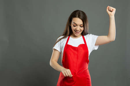 Back view of female supermarket employee holding lower back like hurting on gray background with...