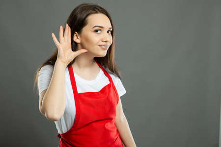 Back view of female supermarket employee holding lower back like hurting on gray background with...