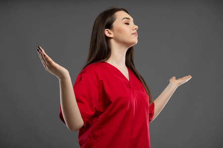 Beautiful young nurse wearing red scrubs giving thumbs up and isolated on a black backgroundの写真素材