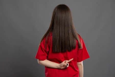 Portrait of an attrative long hair young female nurse making what did you say sign by putting her hand to her ear wearing red scrubsの写真素材