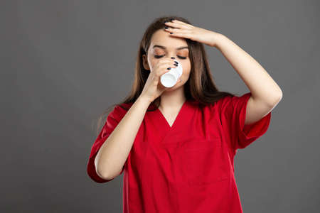 Beautiful young nurse wearing red scrubs giving thumbs up and isolated on a black background