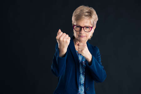 Older blonde businesswoman wants to fight you wearing glasses and a blue jacketの写真素材