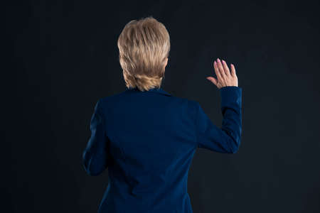 Older secretary swearing in and wearing a blue jacket with blonde hair