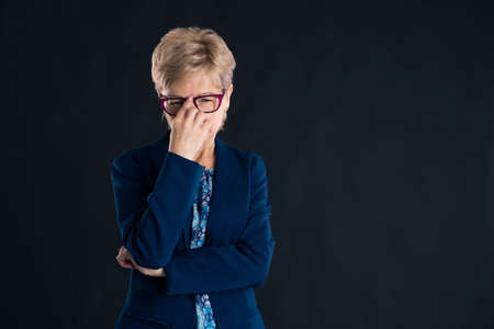 Portrait of an older secretary thinking of something wearing a blue jaket and glasses