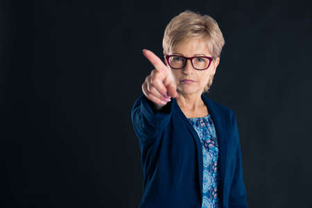Upset secretary saying no on dark background wearing magenta glasees and a blue jacketの写真素材