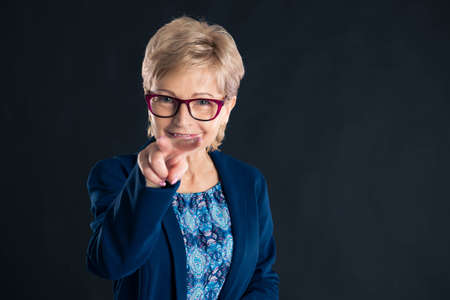 Senior secretary making I see you gesture on a dark backgroundの写真素材