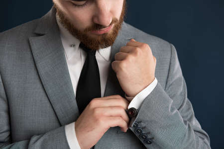 Closeup of handsome businessman fixing his shirt wearing a grey jacket