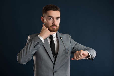 Upset young entrepreneur saying that it's time to call me wearing a grey suitの写真素材