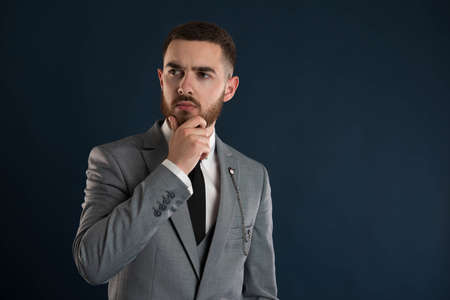 Handsome young businessman thinking about a deal wearing a grey suit and black tieの写真素材