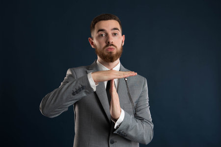 Young businessman calling for a timeout wearing a grey suit and black tieの写真素材