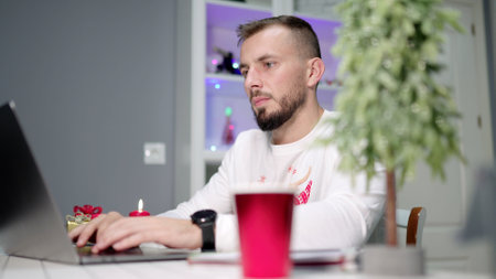 Focused freelancer working on laptop during christmas season at home
