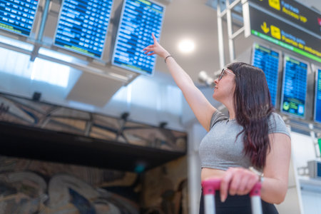 Traveler looking for her flight information on the airport information board