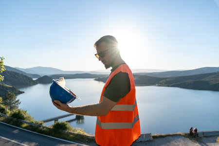Engineer holding safety helmet at dam construction siteの写真素材