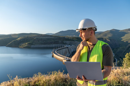Engineer inspecting dam with laptop for workplace safetyの写真素材