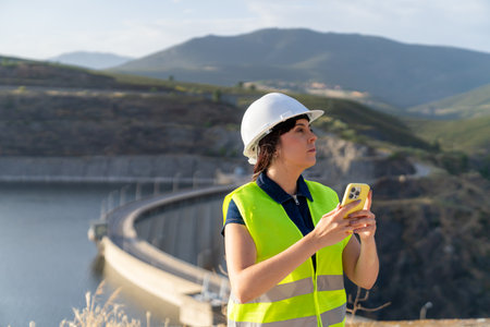 Female engineer inspecting dam using mobile phone