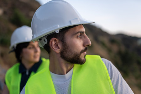 Young adult engineers wearing safety helmets inspecting construction siteの写真素材