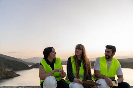 Engineers discussing project details at sunset by the lakeの写真素材