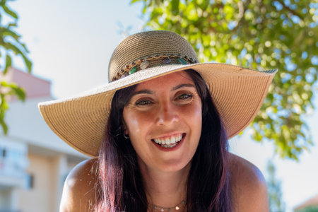 Happy tourist woman smiling and wearing a sun hat outdoorsの写真素材