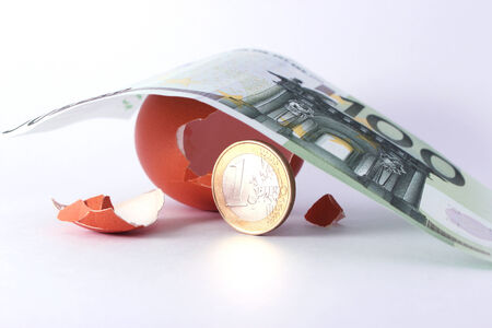 1 Euro coin getting out of cracked hatched egg under 100 euro banknote. Symbol for investment,...