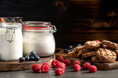 Raspberries, blueberries and homemade cookies placed on wooden plattersの写真素材