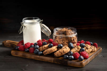 Biscuits, berries and milk on wooden bottom, side view.の写真素材