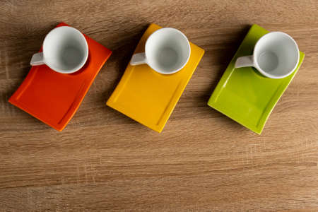 Table top view of three white coffee cups placed on coloured dishware.の写真素材