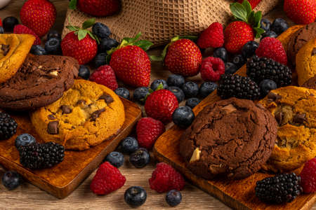Chocolate biscuits on wooden platter with forest fruits close-upの写真素材