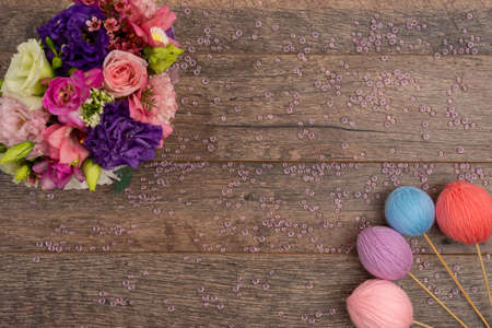 Colorful yarn balls and fresh bouquet of flowersの写真素材