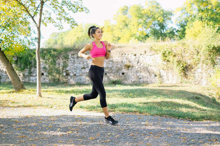 Sport girl is running in park and smiling